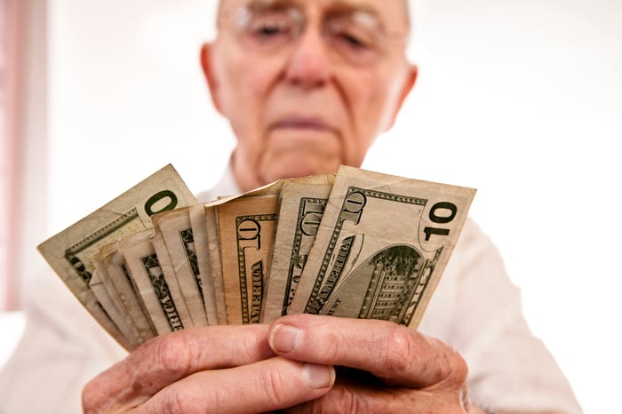 A person counting a fanned pile of assorted cash bills.