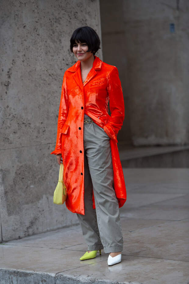 Maria Bernad в серых брюках, оранжевый лакированный плащ и туфли разного цвета
