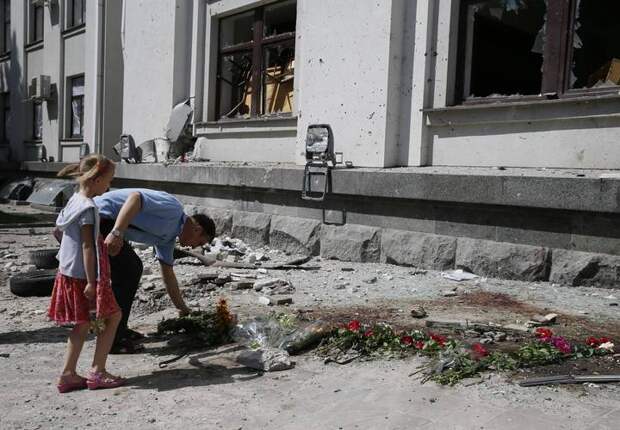 A man places flowers near the site of an explosion in a regional administration building in Luhansk