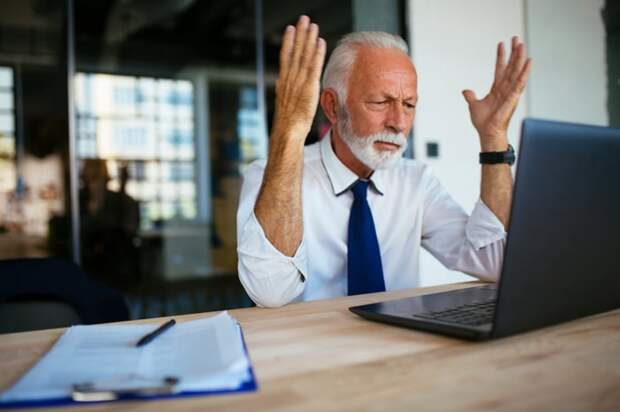 A person at a laptop raising their arms as if annoyed.