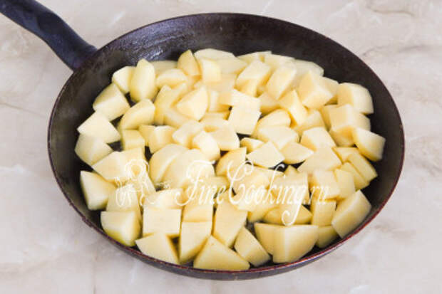 Подливаем еще растительного масла, даем ему как следует прогреться и выкладываем в сковороду кусочки картофеля