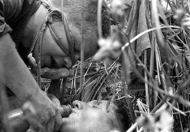 Легкораненый американский морпех поит водой своего тяжело раненого товарища во время спецоперации вдоль демилитаризованной зоны между Севером и Югом Вьетнама, 21 июля 1966 года.