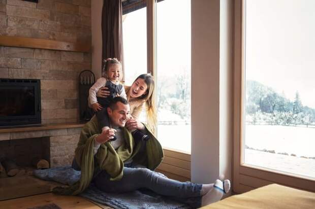 Young family bundled up in warm clothes by a window.