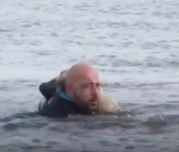 Мужчина в куртке в воде Мужчина тащит собаку
