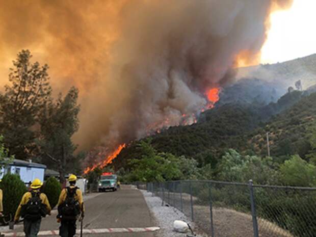 a photo of firefighters with the Carr Fire in the background