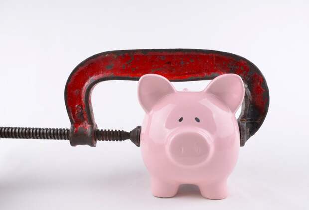 Clamp squeezing a piggy bank.