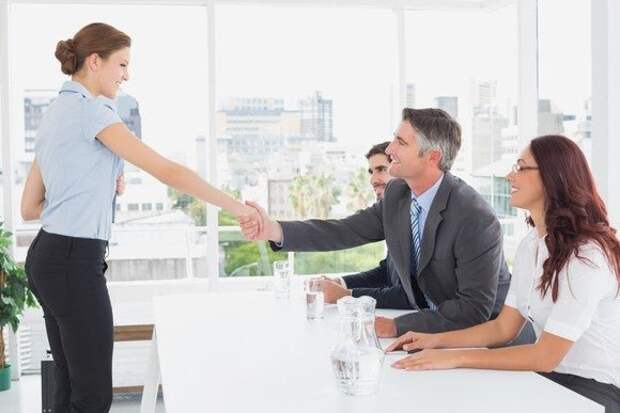 Woman shaking hands with employer during job interview.