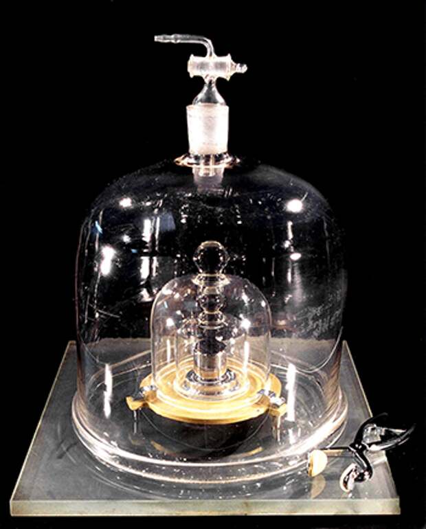 A photo showing the way the kilogram standard is stored and protected, under a glass jar and in a vault.
