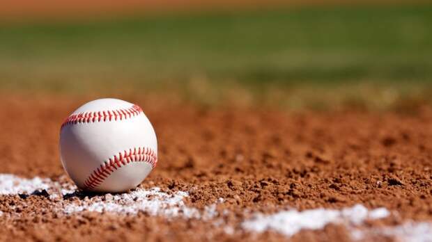 A baseball rests on the edge of the infield.