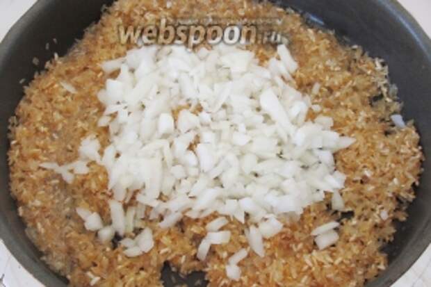 Когда рис подрумянится, добавим нарезанный лук. Обжариваем рис вместе с луком в течение примерно 3 минут, пока лук не станет мягче.