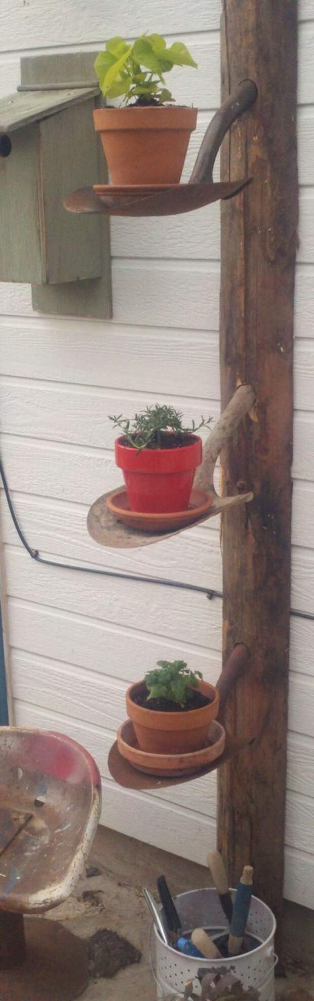 Old post + old shovel heads = rustic garden shelves.  Would look great with hanging flower baskets.: 