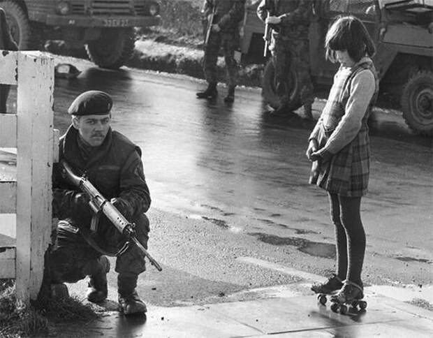 Девочка бесстрашно смотрит на солдата, который патрулирует в Северной Ирландии, 1969 демонстрации, женщины, кадры, общество, протест, сильные женщины, сильные фотографии, фото