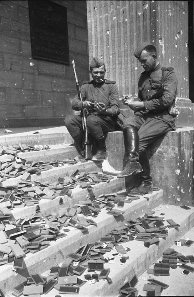 Советские солдаты сидят на ступенях разрушенного Рейхстага и рассматривают не врученные фашистские награды, 1945 год история, события, фото