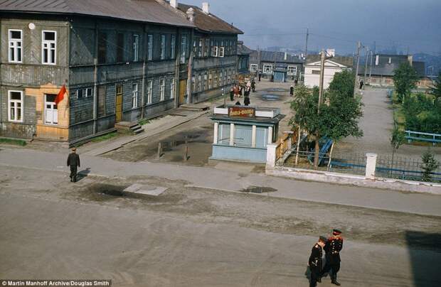Russian officials are photographed from a window above the street in Murmansk, a small port city in the extreme northwest part of Russia. The run down houses are made from wooden planks and a small, blue beer shack sits outside.  The almost empty street was captured by the US diplomat Mr Manhoff who was later deported on suspicion of spying