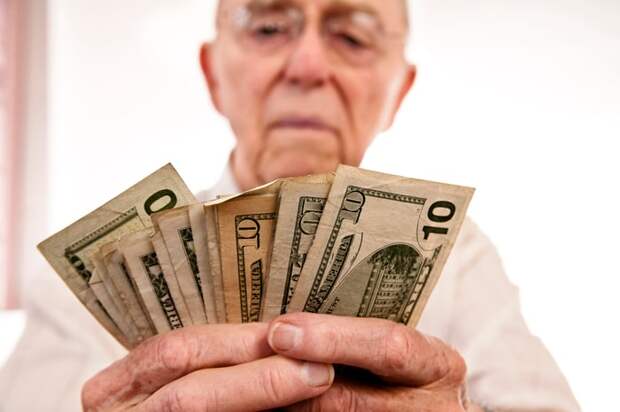 A person holding an assortment of fanned cash bills in their hands. 