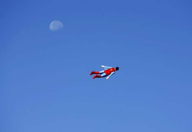 A radio-controlled Superman plane, flown by designer Otto Dieffenbach, passes the moon during a test flight in San Diego on June 27, 2013. (REUTERS / Mike Blake)