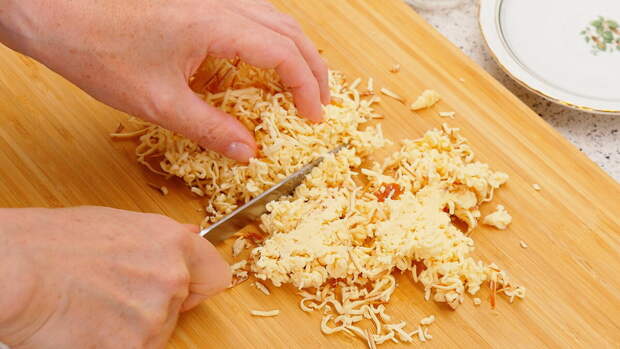 150 грамм колбасного сыра натираем на мелкой тёрке. И после мелкой тёрки ещё рубим натёртое ножом, потому что полосочки сыра получаются длинноватыми. 