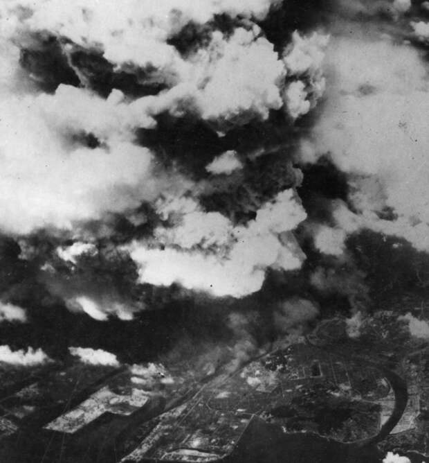 7. Фото, сделанное из одного из двух американских бомбардировщиков 509-ой сводной группы, вскоре после 8:15, 5 августа 1945 года, показывает поднимающийся от взрыва дым над городом Хиросима. К моменту съемки уже произошла вспышка света и жара от огненного шара диаметром 370 м, и взрывная волна быстро рассеивалась, уже причинив основной вред зданиям и людям в радиусе 3,2 км. (U.S. National Archives)