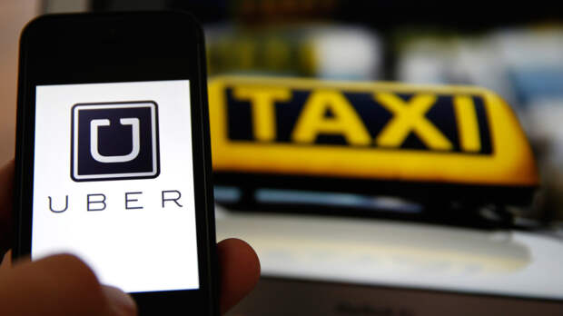 An illustration picture shows the logo of car-sharing service app Uber on a smartphone next to the picture of an official German taxi sign