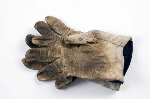 an old and very dirty work glove lies on a white background - грязная перчатка стоковые фото и изображения