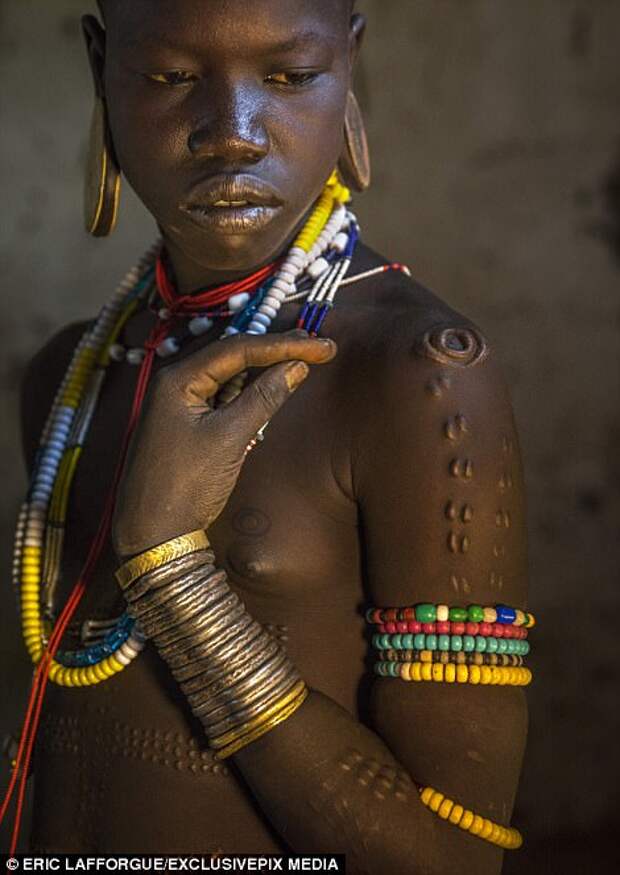 A 12-year-old girl was pictured after she took part in her tribes scarification process by photographer Eric Lafforgue. He said that she was silent and 'showed no pain' through the 10 minute cutting process in the Omo valley in Ethiopia