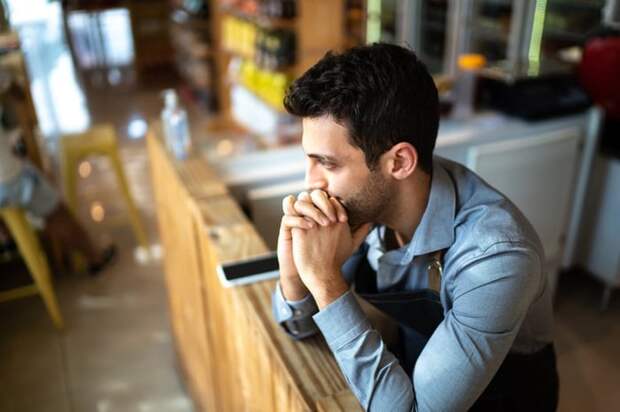 A worried person in an office leaning their chin on their hands.