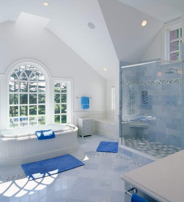 Просторная ванная в частном доме с белой сантехникой и яркими синими акцентами на элементах декоора
