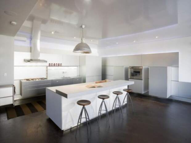 Контрастный дизайн кухни в стиле контемпорари с напольным покрытием из темного дерева и белой  мебелью 