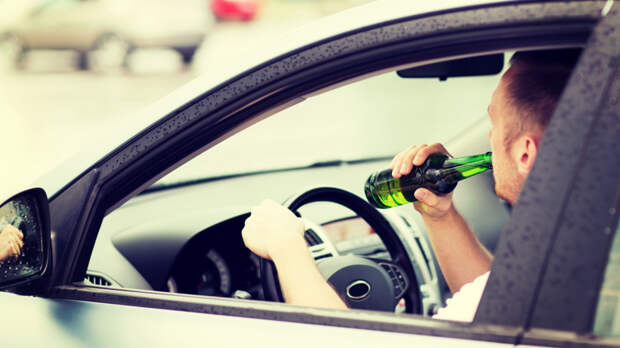 man drinking alcohol while driving the car