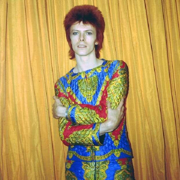 Легендарный певец в ярком стеганом костюме, созданном для тура «Ziggy Stardust» позирует в гостиничном номере в Нью-Йорке. Легендарный певец в ярком стеганом костюме, созданном для тура «Ziggy Stardust» позирует в гостиничном номере в Нью-Йорке.