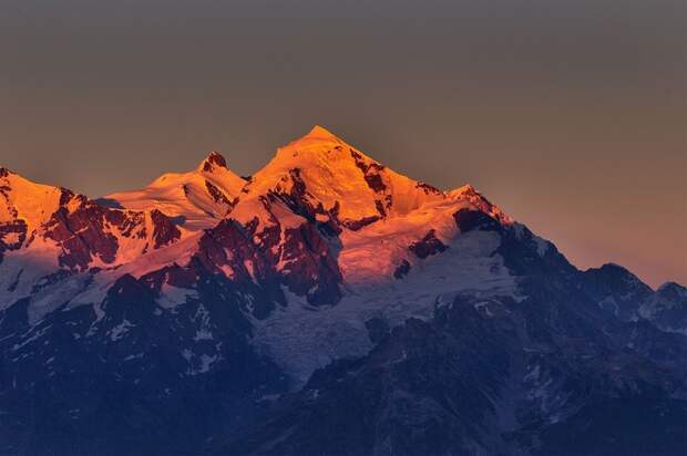 Окрашенные лучами восходящего солнца ледники на вершине гор очень напоминают расплавленное золото.