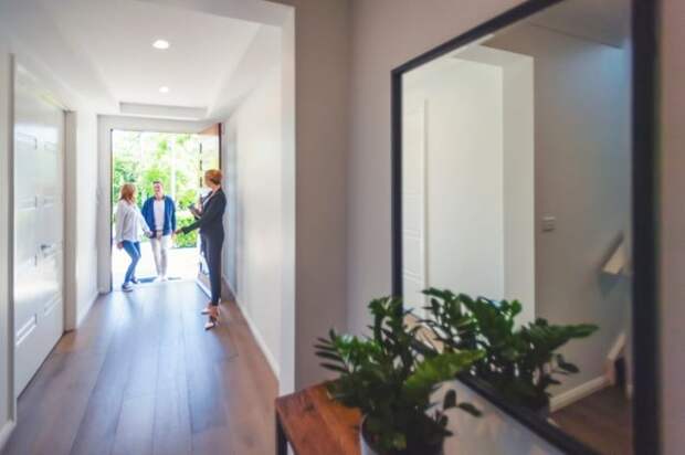 Two people walking in the front door of a house with a Realtor.